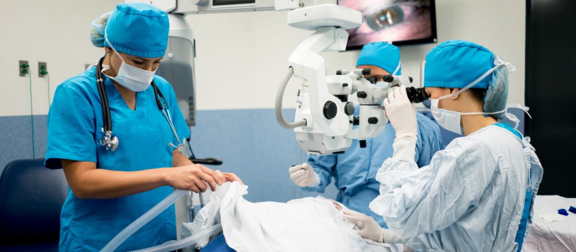 Ophthalmic surgeon performing an eye surgery at the hospital with a microscope - healthcare and medicine concepts