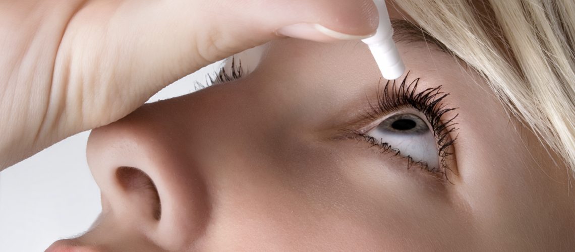 woman applying eyedroppes, close up